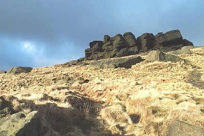 Edale Rocks stand out against a dark wintry sky