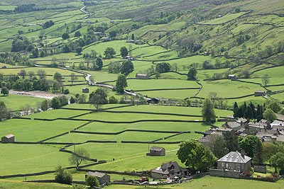 Fields separate the River Swale from the village of Muker