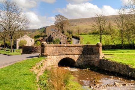 Bridge over Downham Beck with Pendle Hill in the background
